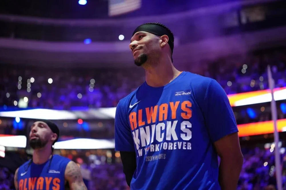Josh Hart, in an Always Knicks T-shirt, looks on before a Knicks-76ers game.